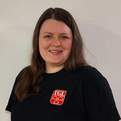 Eine Tänzerin in einem schwarzen TGL-Shirt lächelt stolz und repräsentiert den Sportverein in Landshut.