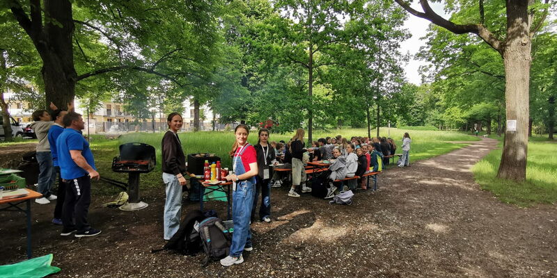 Im Park grillen Mitglieder des Turngemeinde Landshut Vereins gemeinsam und genießen geselliges Beisammensein.