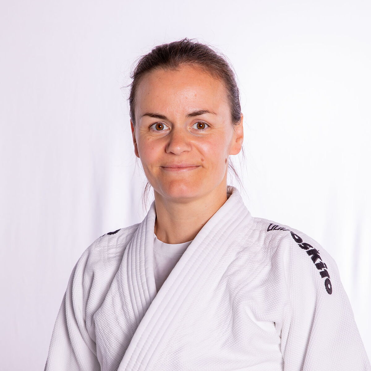 Eine Frau im Judoanzug lächelt stolz, repräsentiert den Sportverein Turngemeinde Landshut.