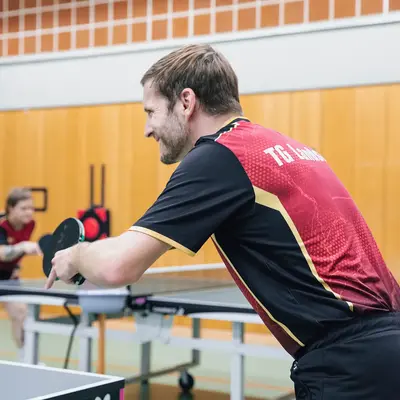 Zwei Spieler des Turngemeinde Landshut Vereins konzentrieren sich beim Tischtennisspiel in der Sporthalle.