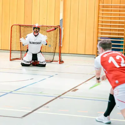 Ein Spieler der Turngemeinde Landshut schießt im Hallensport auf das Tor, während der Torwart bereit ist zu parieren.