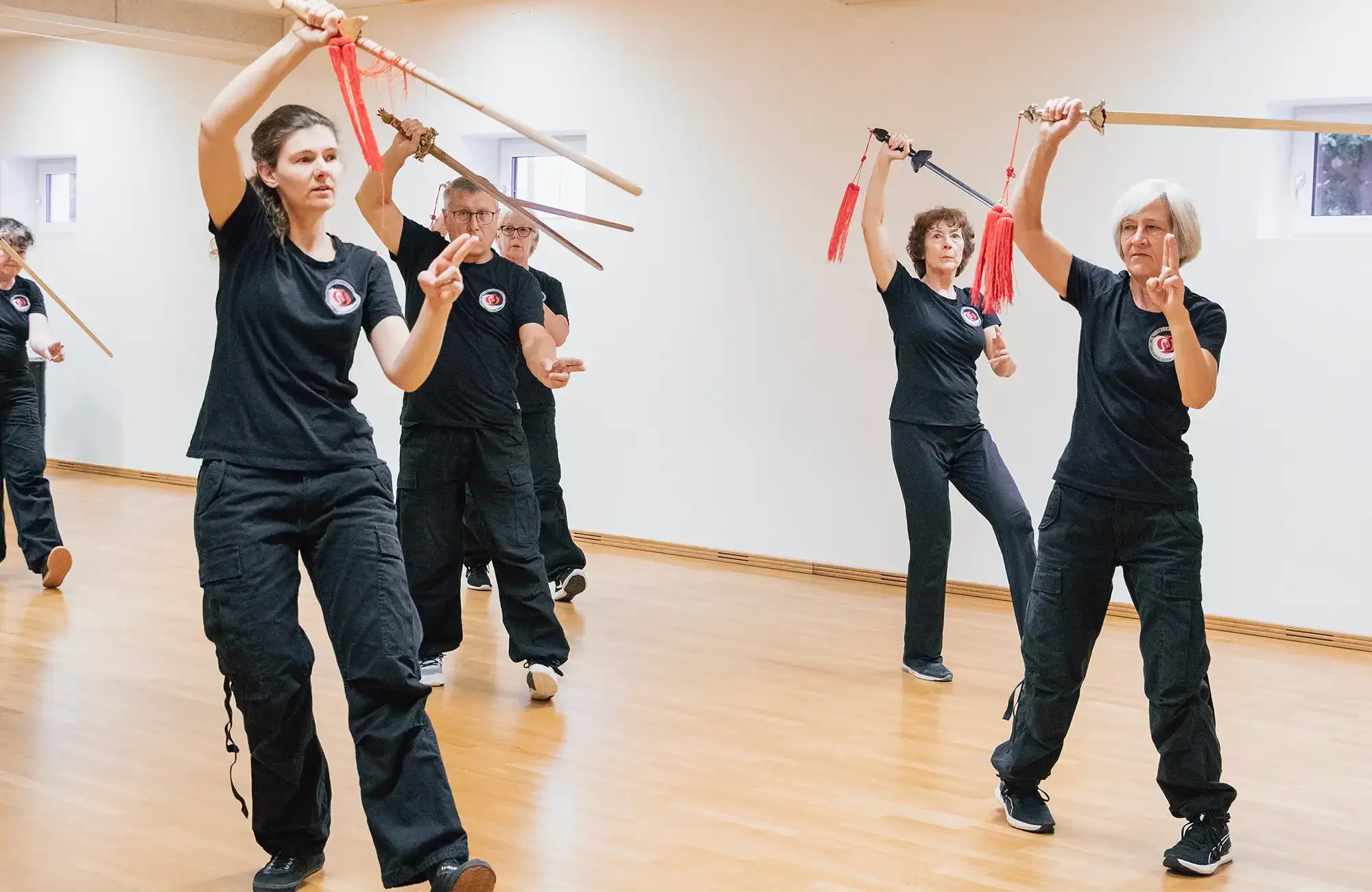 Eine Gruppe von Menschen übt Schwertkunst in einem hellen Raum beim Turngemeinde-Verein.