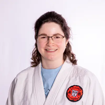 Eine Frau in einem weißen Judoanzug mit dem Logo der Turngemeinde Landshut lächelt in die Kamera.