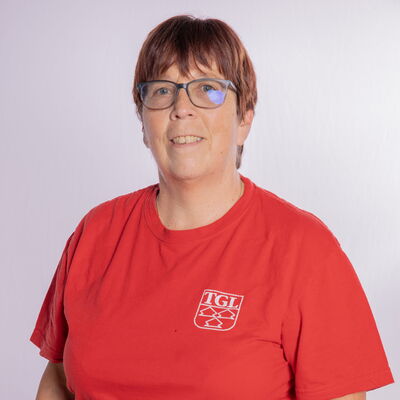 Eine Frau in einem roten TGL-Shirt der Turngemeinde Landshut lächelt vor einem neutralen Hintergrund.