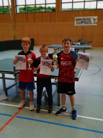 Drei Jungen präsentieren stolz ihre Pokale und Urkunden bei einem Tischtennisturnier der Turngemeinde Landshut.
