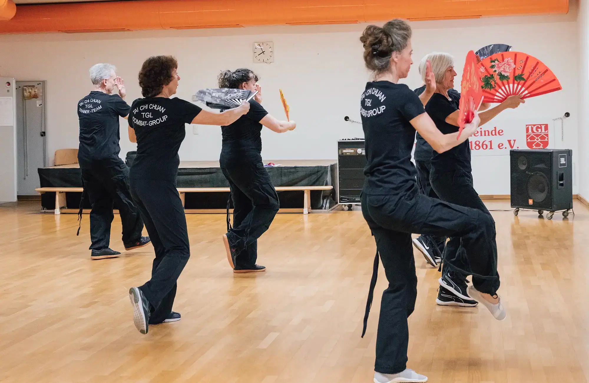 Eine Gruppe von Menschen übt Tai Chi mit Fächern im Turngemeinde Landshut Verein.
