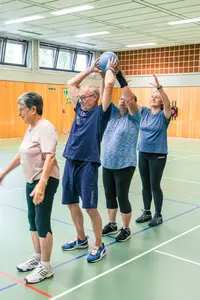 Eine Gruppe älterer Menschen trainiert mit einem Ball in der Turnhalle der Turngemeinde Landshut.