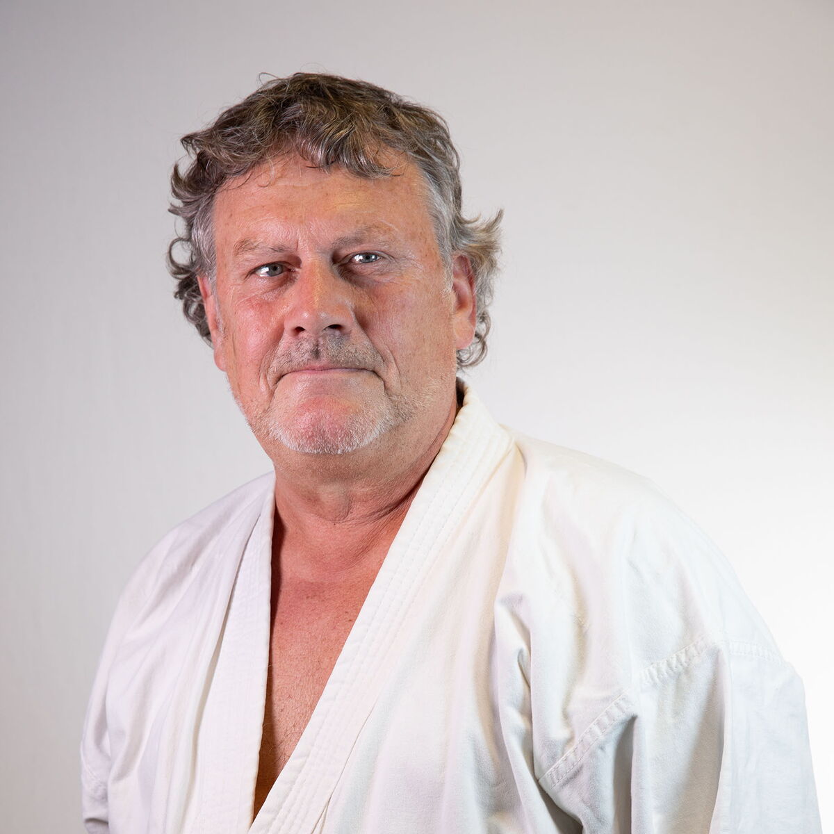 Ein Mann in Karate-Kleidung blickt ernst und fokussiert, passend zur Turngemeinde Landshut.