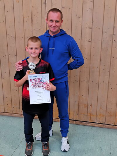 Ein Junge hält stolz eine Urkunde und einen Pokal im Sportverein Turngemeinde Landshut.