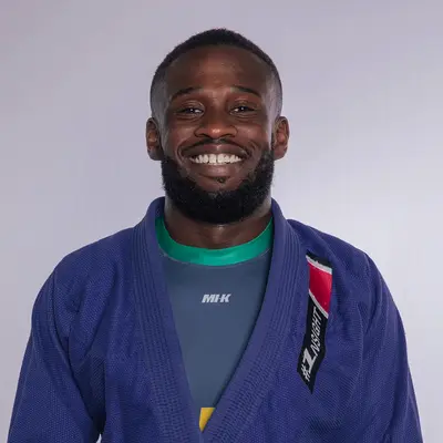 Ein Mann in einem blauen Judoanzug lächelt stolz, als er seine Verbindung zum Sportverein Turngemeinde zeigt.