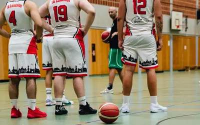 Basketballspieler des Turnvereins Landshut versammeln sich in der Halle für eine Besprechung mit ihrem Trainer.