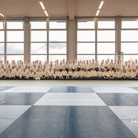 Man sieht zirka 60 Aikidokas sitzend im Seiza posierend für ein Gruppenbild.