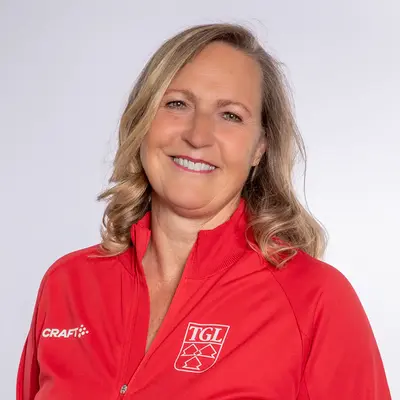 Eine lächelnde Frau trägt eine rote TGL-Jacke, symbolisierend den Sportgeist des Vereins Turngemeinde Landshut.
