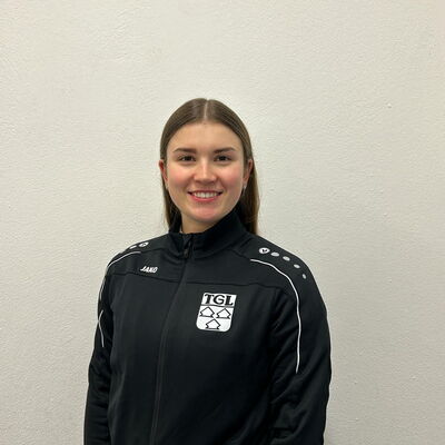 Eine lächelnde Frau in TGL-Sportkleidung repräsentiert stolz ihren Verein.