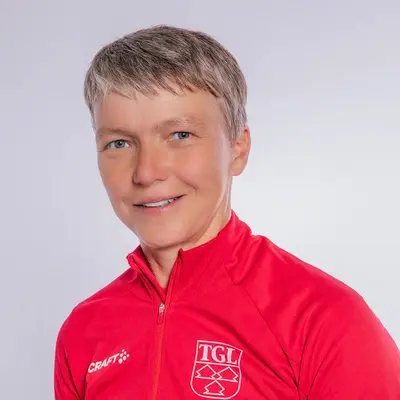 Eine Frau in roter TGL-Sportjacke lächelt freundlich in die Kamera, symbolisiert den Verein Turngemeinde Landshut.