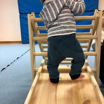 Ein Kleinkind klettert in einem Babykurs der Turngemeinde Landshut eine kleine Holzleiter hoch.