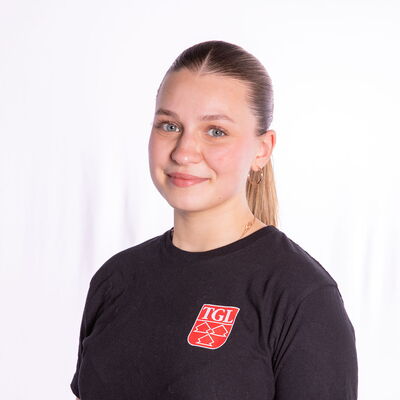 Eine Tänzerin in einem schwarzen TGL-Shirt lächelt stolz und repräsentiert den Sportverein in Landshut.