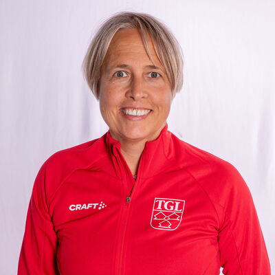 Eine lächelnde Frau trägt eine rote TGL-Jacke, symbolisierend den Sportgeist des Vereins Turngemeinde Landshut.