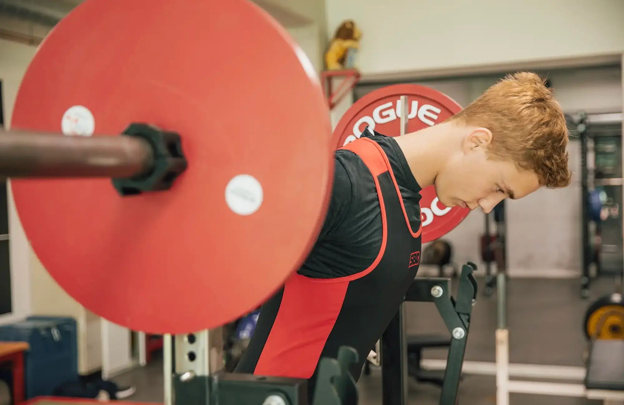 Ein junger Athlet der Turngemeinde hebt konzentriert eine schwere Langhantel im Fitnessstudio des Vereins.