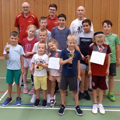 Eine Gruppe von Kindern und Erwachsenen hält Pokale und Urkunden bei einer Tischtennisveranstaltung des Vereins Turngemeinde Landshut.