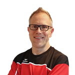 Eine lächelnde Frau im TGL-Sporttrikot steht vor einem neutralen Hintergrund.