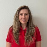 Eine Frau in einem roten TGL-Shirt lächelt in die Kamera, repräsentiert den Sportverein Turngemeinde Landshut.
