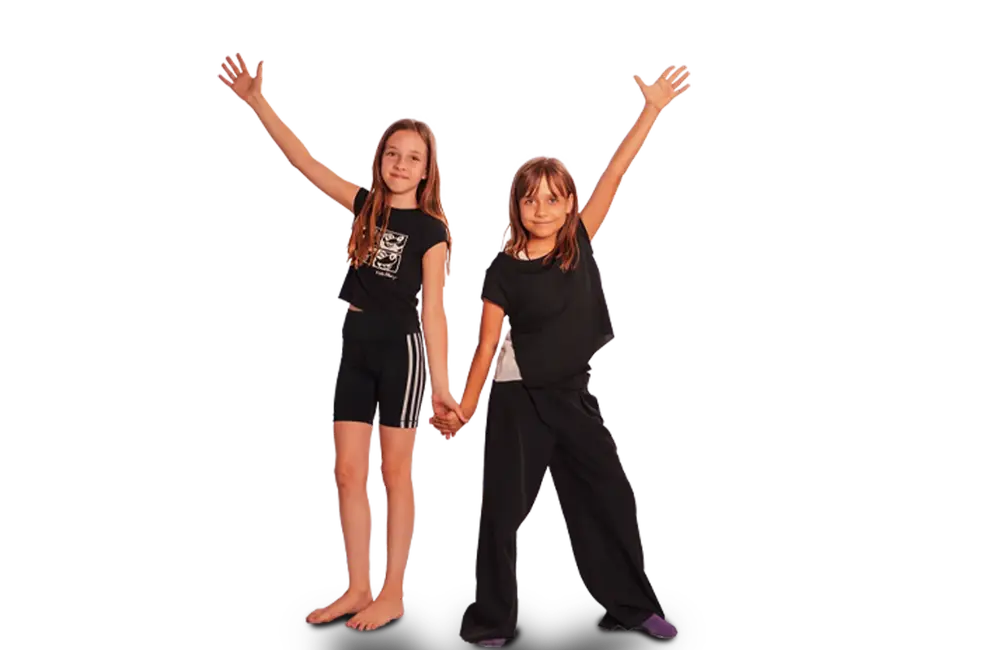 Zwei Mädchen halten sich die Hand und strecken fröhlich die Arme in die Luft, symbolisierend den Teamgeist der Turngemeinde Landshut.