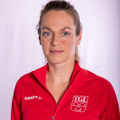 Eine lächelnde Frau trägt eine rote TGL-Jacke, symbolisierend den Sportgeist des Vereins Turngemeinde Landshut.