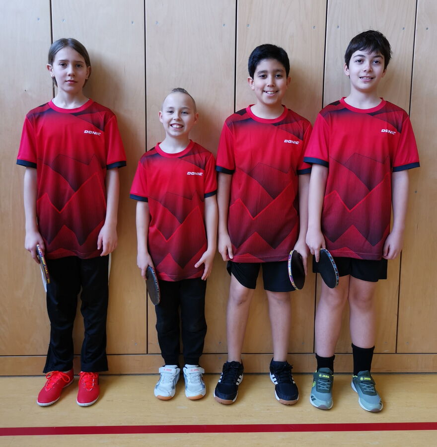 Eine Gruppe junger Tischtennisspieler der Turngemeinde Landshut posiert mit Schlägern in einer Sporthalle.