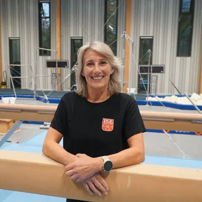 Eine lächelnde Frau im roten TGL-Shirt präsentiert stolz ihre Zugehörigkeit zum Sportverein.