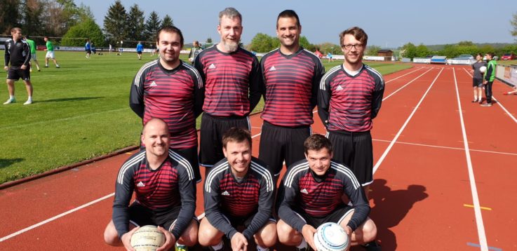 Eine Sportmannschaft der Turngemeinde Landshut posiert lachend in ihren Vereins-Trikots auf einer Laufbahn.