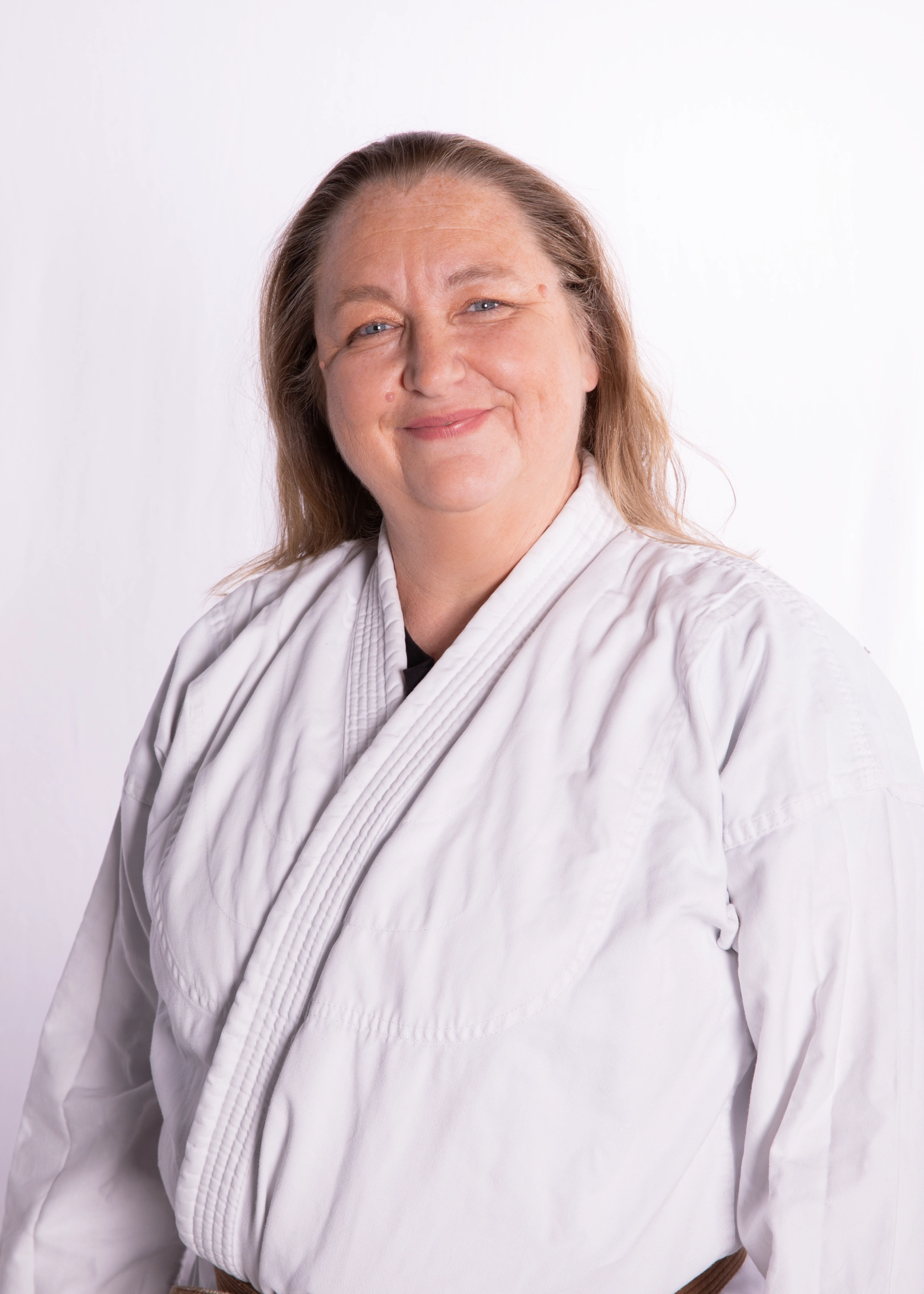 Eine Frau in einem weißen Judogi lächelt freundlich, möglicherweise ein Mitglied der Turngemeinde in Landshut.