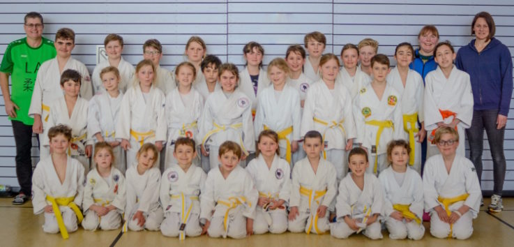 Eine Gruppe von Kindern in weißen Judoanzügen posiert für ein Mannschaftsfoto im Verein Turngemeinde Landshut.