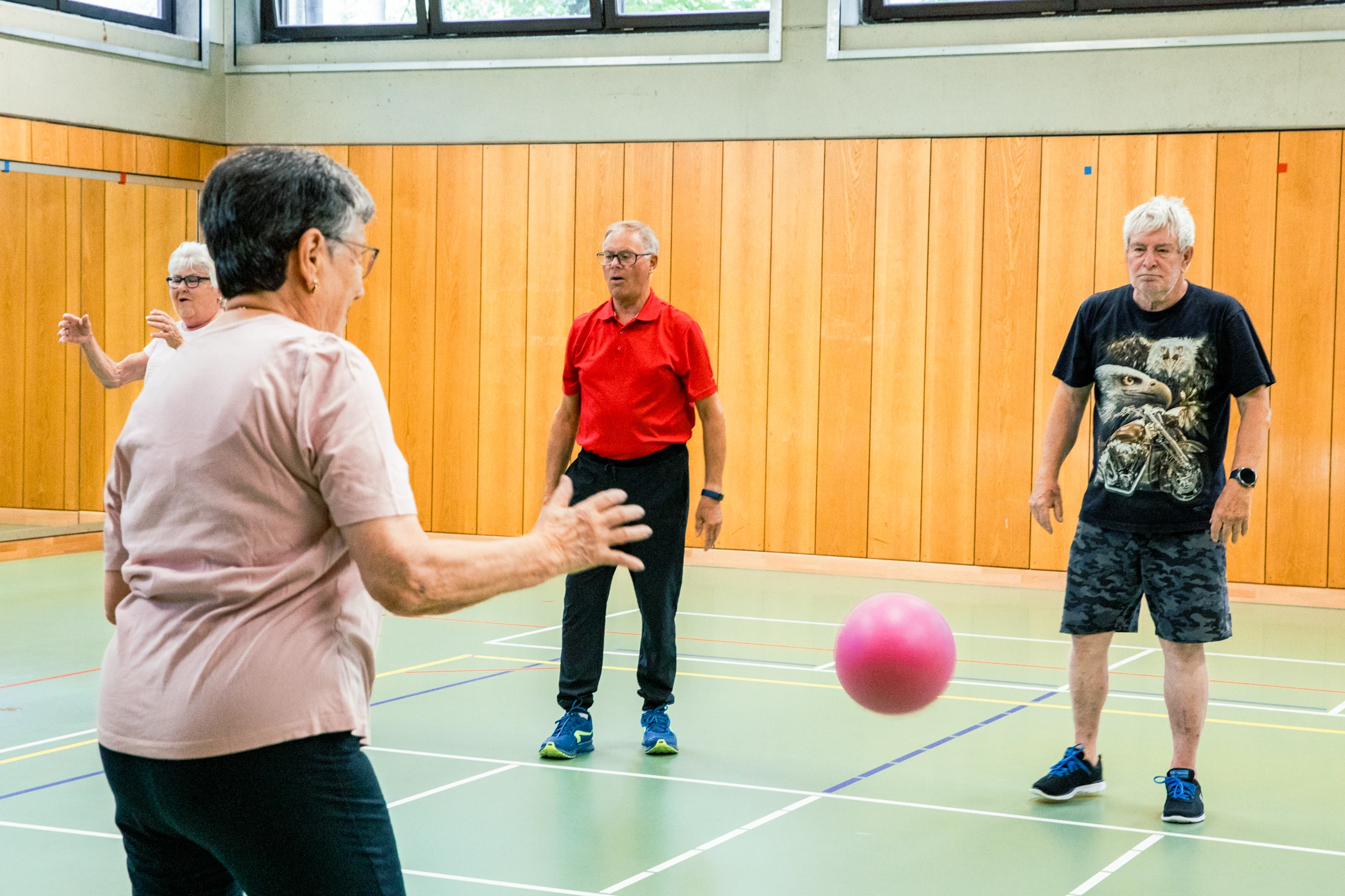 Senioren spielen mit einem Ball in einer Sporthalle der Turngemeinde Landshut und fördern so ihre Fitness im Verein.