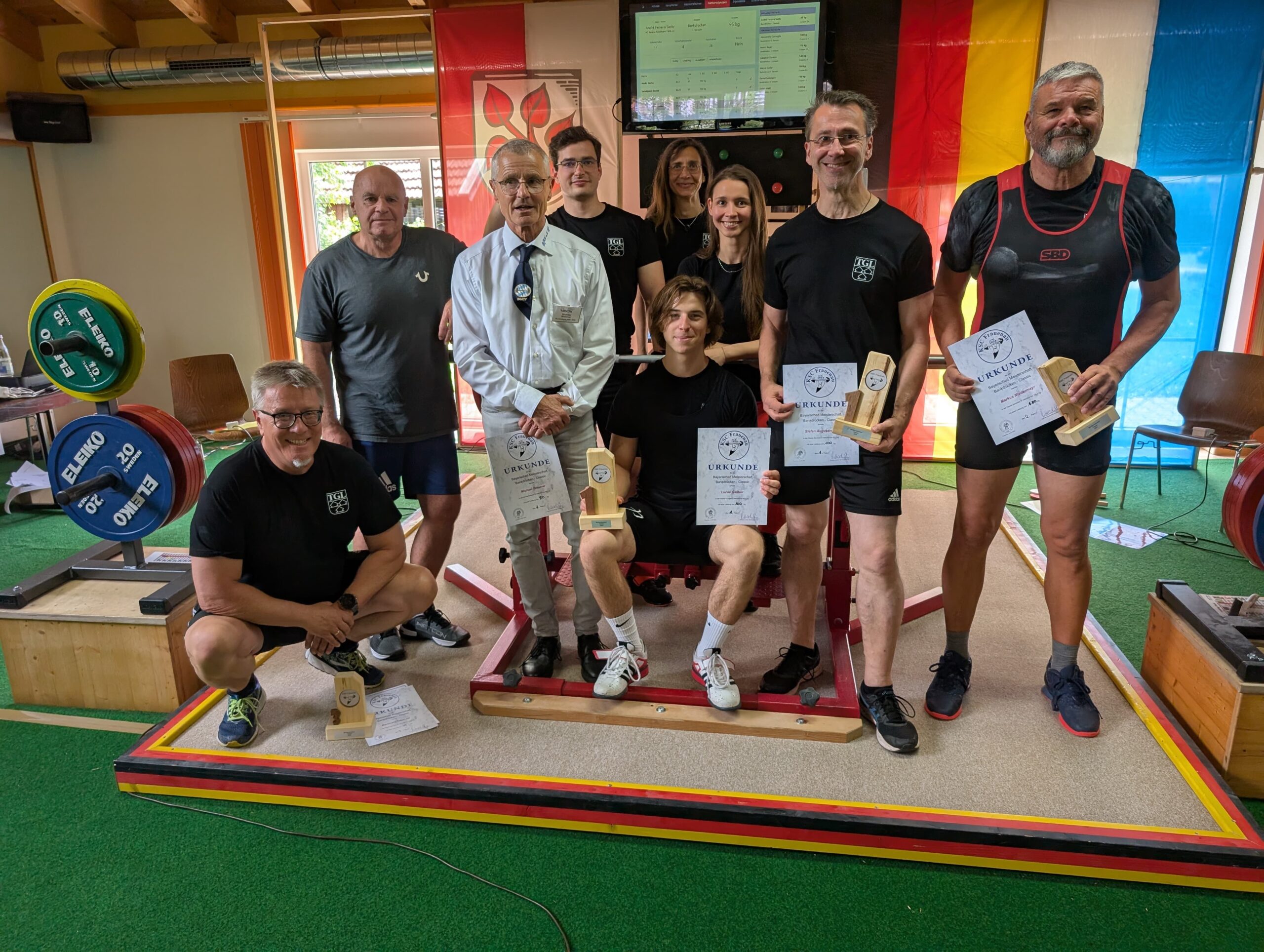 Eine Gruppe von Sportlern der Turngemeinde Landshut präsentiert stolz ihre Urkunden und Trophäen nach einem Wettkampf.