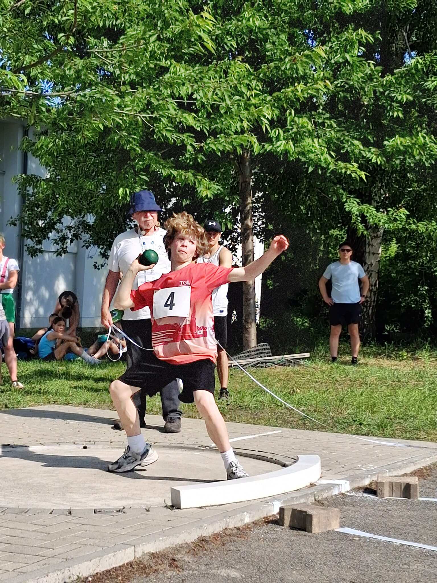 Ein Sportler von der Turngemeinde Landshut stößt beim Wettkampf die Kugel mit voller Kraft.
