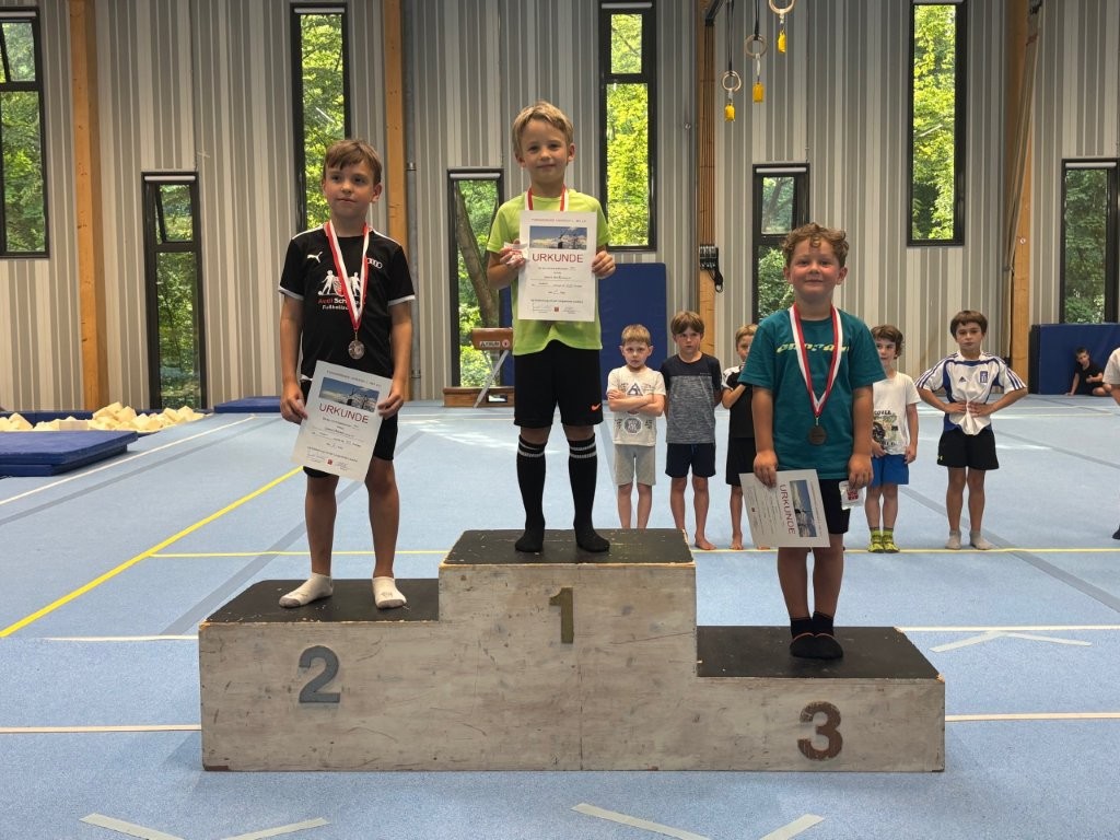 Drei junge Sportler auf dem Siegerpodest mit Urkunden und Medaillen beim Turnierevent der Turngemeinde Landshut.