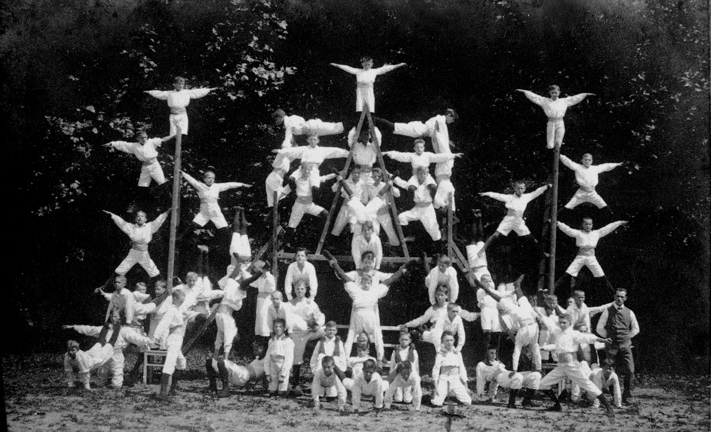 Eine Gruppe von Athleten der Turngemeinde Landshut formt eine beeindruckende menschliche Pyramide im Freien.